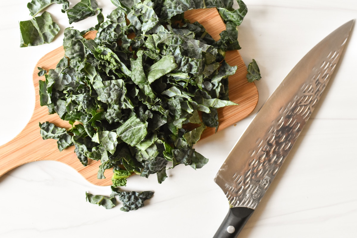 shredded kale on a cutting board with knife