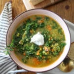 Pea soup in a pink ceramic bowl with kale and sausage