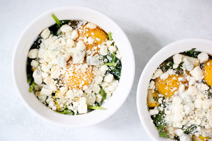 blue cheese sprinkled on top of eggs and greens ramekins