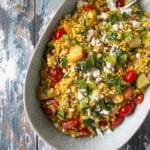 Couscous salad in a blue bowl with vegetables and herbs