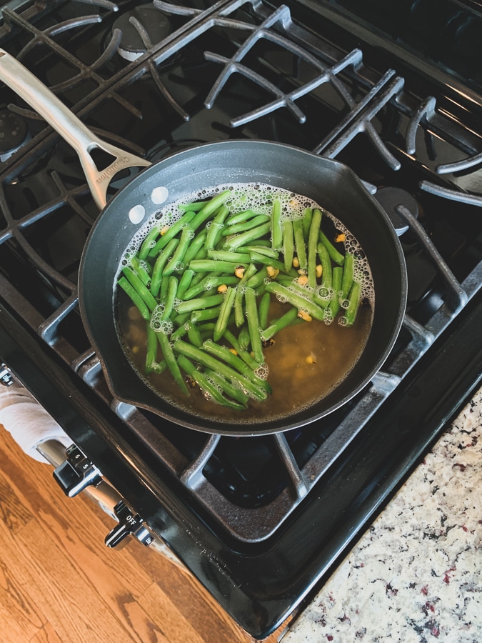 Green beans floating in boiling water on a gas stovetop