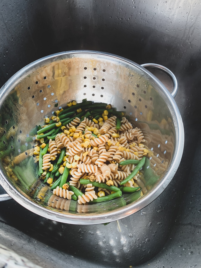 rotini, corn, and beans in a colander in the sink