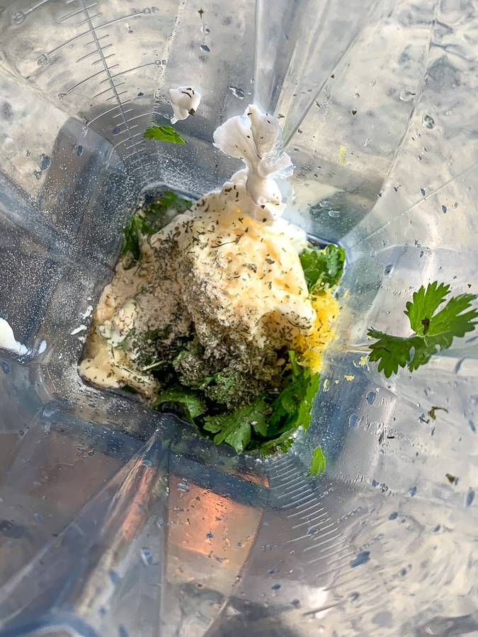 blender with unblended salad dressing ingredients like sour cream, dill, fresh herbs, and lemon zest