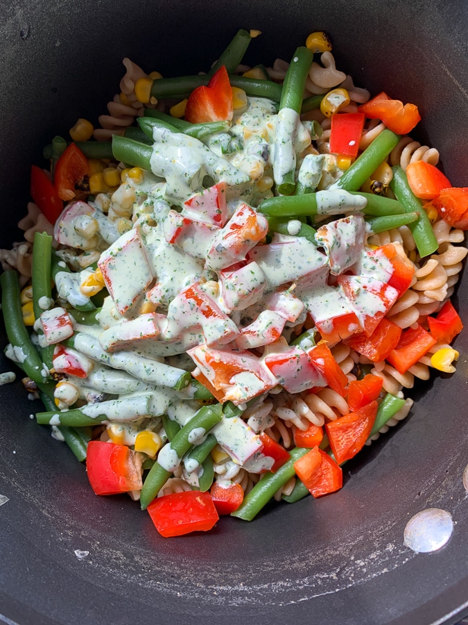 rotini, peppers, beans, and corn with a herb dressing poured on top