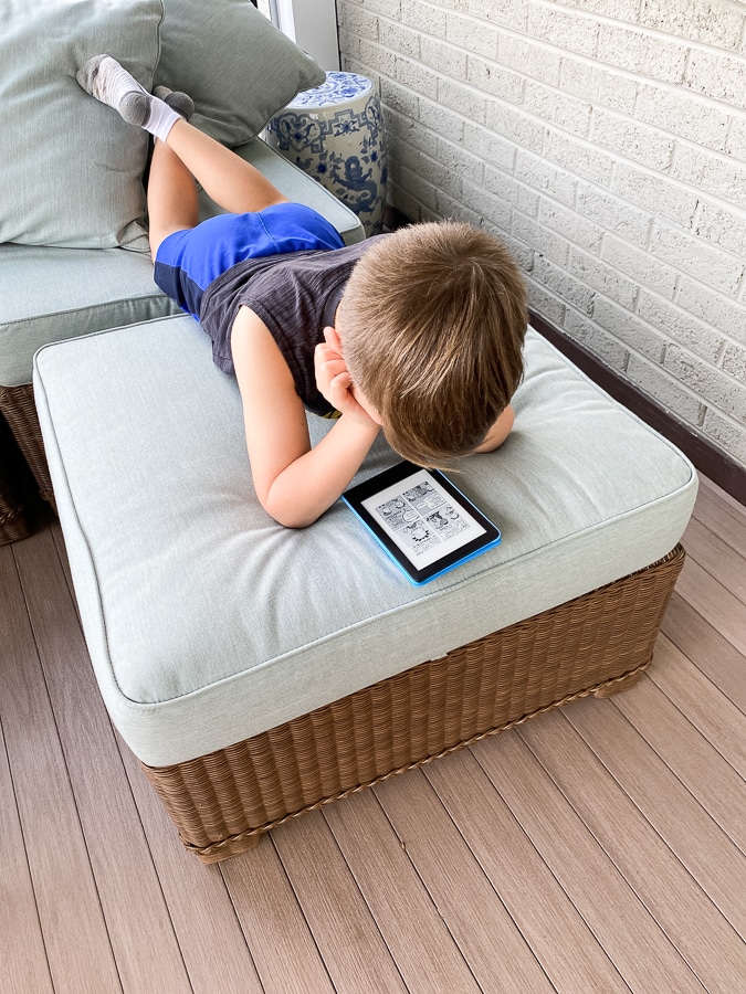 child reading kindle on ottoman