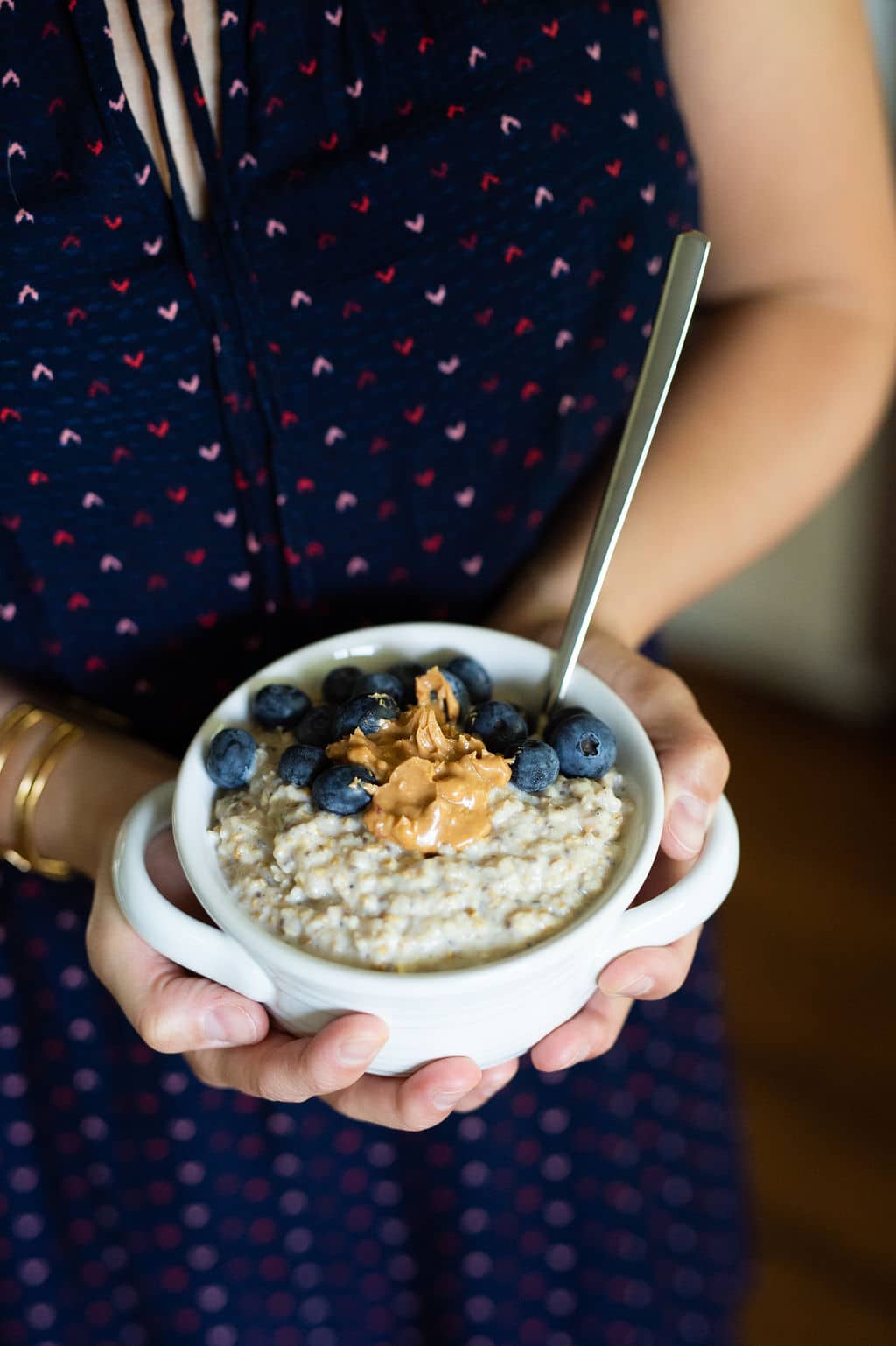 kath holding a bowl of oatmeal with peanut butter and blueberries