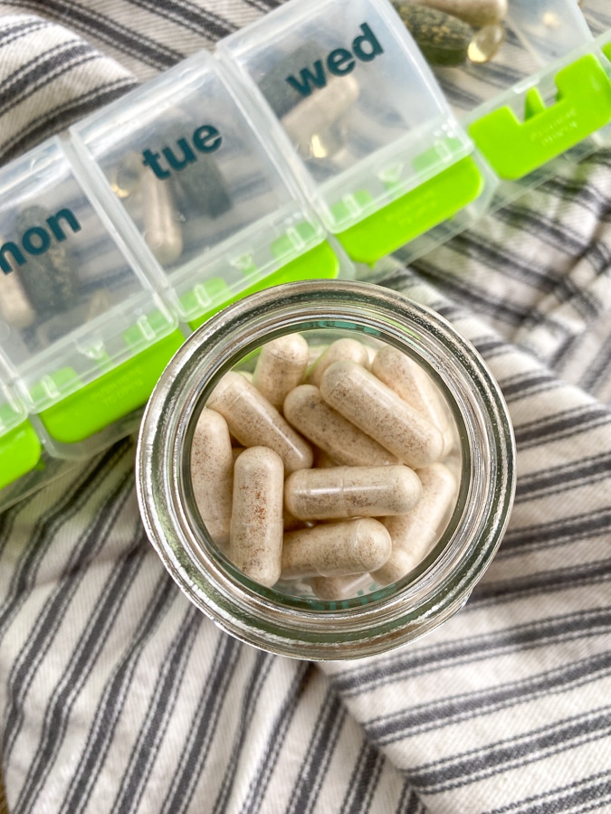 Routine probiotics in a glass jar next to a pill case