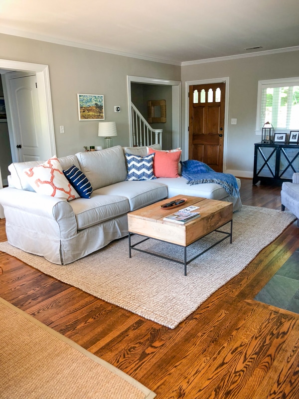 Pottery Barn sectional with nautical throw pillows in neutral living room.