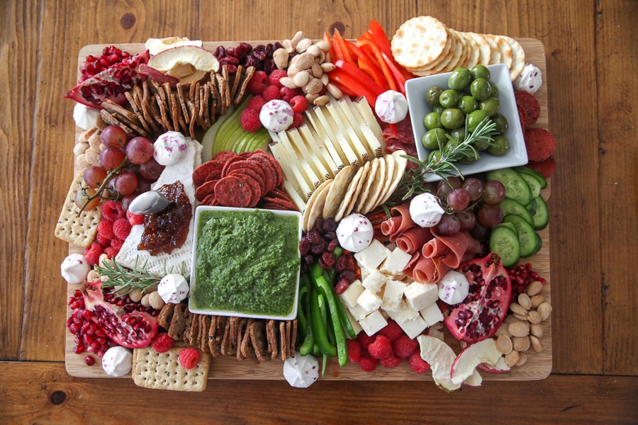 finished cheese board with cheese, meats, fruits, veggies, nuts, dips, crackers, meringues