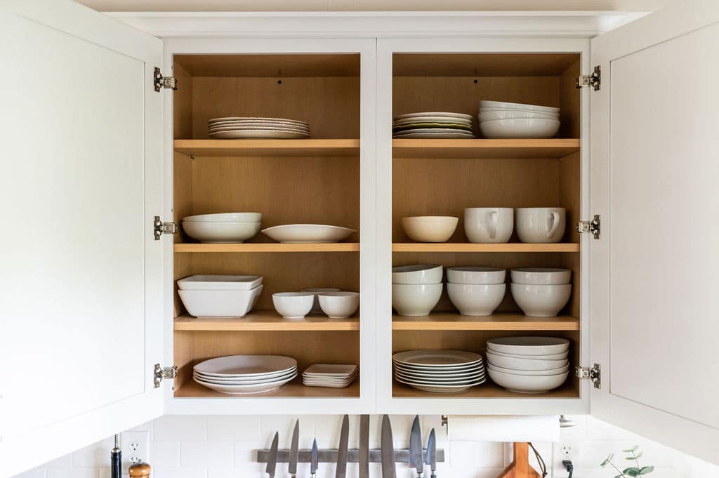 Open kitchen cupboards Open kitchen cupboards with white stacks of white plates and bowls.