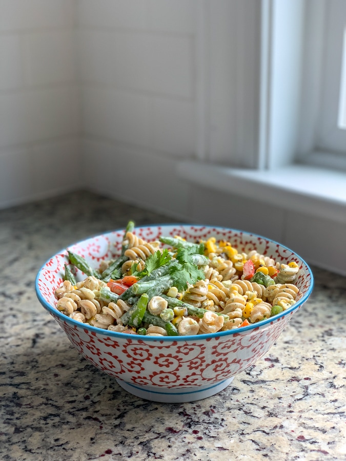 summer pasta salad in red and blue ceramic serving bowl