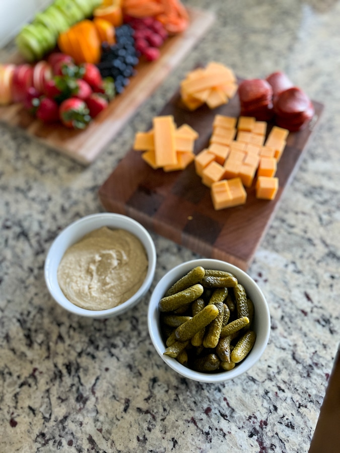 Kids Charcuterie Board prep with cheese, pickles and hummus in bowls