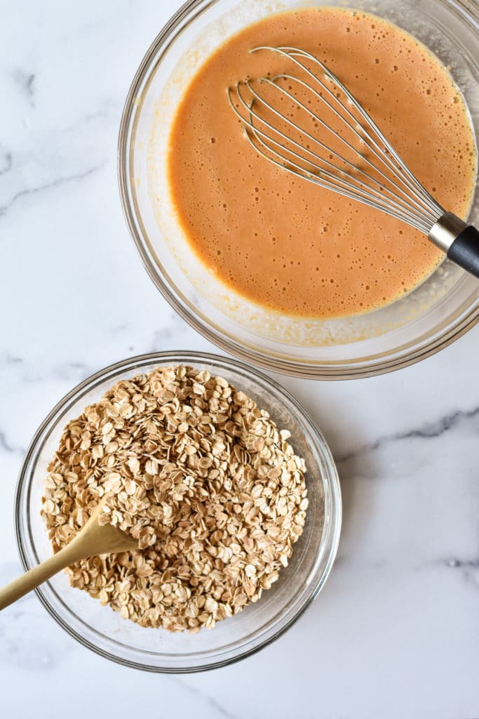 oats in one bowl and liquid ingredients in a separate bowl with whisk