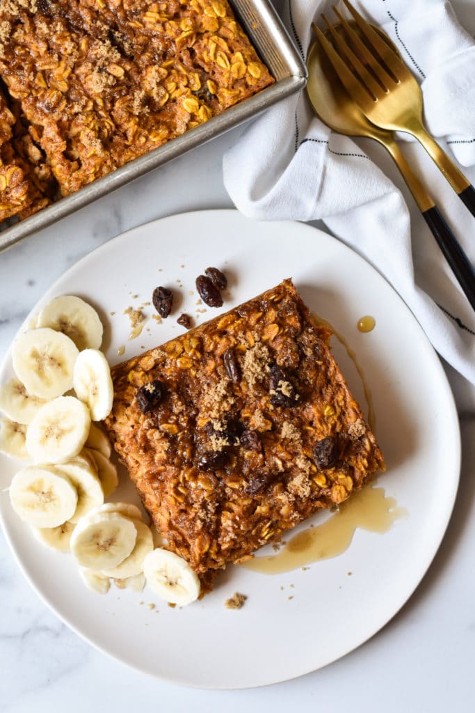 pumpkin baked oatmeal square on a plate with banana slices and raisins