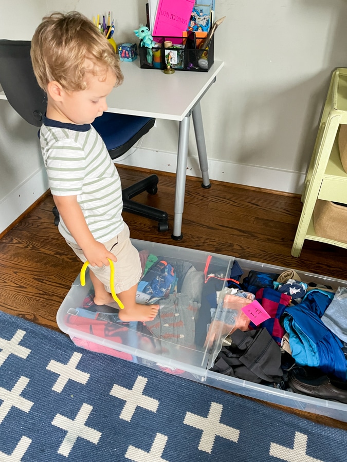 toddler standing on an underbed storage bin