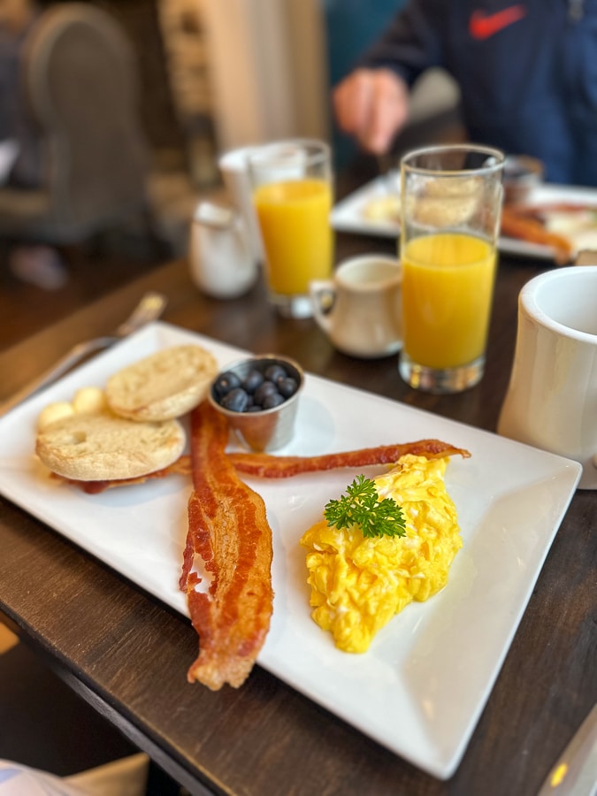 eggs and bacon breakfast eggs, bacon, fruit, and a toasted English muffin