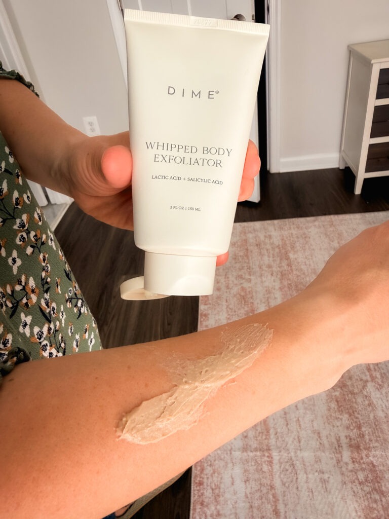 Dime Whipped Body Exfoliator smeared on an arm in a bedroom