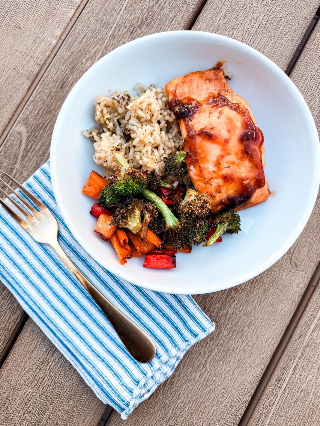 teriyaki salmon in a bowl with roasted broccoli, peppers, and rice